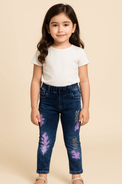 Close-up of a child wearing dark blue jeans with iridescent, purple, and pink celestial or galaxy-like patterns on the legs.