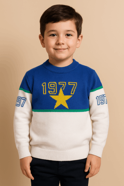 A young boy wearing a blue, green, and off-white color-block sweater with a yellow star and the number "1977" on the chest, and "97" on the sleeves.