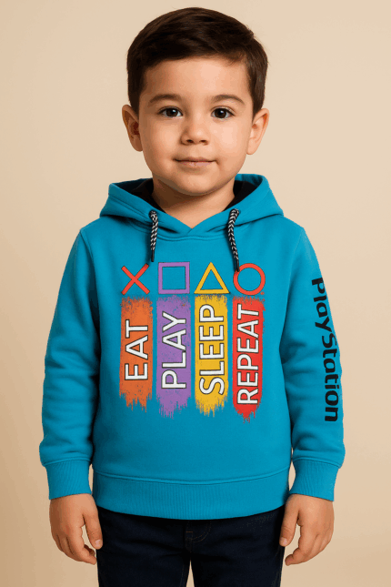 A young boy wearing a bright blue hoodie with "EAT PLAY SLEEP REPEAT" in colorful vertical bars and PlayStation symbols above, and "PlayStation" written vertically on the right sleeve.