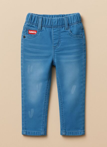 A pair of boys' light blue denim jeans with a slight fade, featuring a red tag near the waistband and visible stitching details.