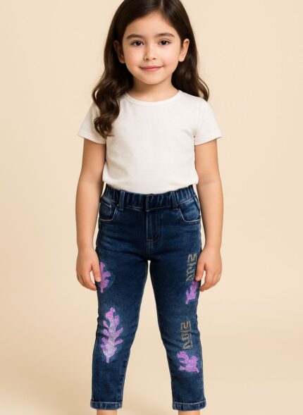 Close-up of a child wearing dark blue jeans with iridescent, purple, and pink celestial or galaxy-like patterns on the legs.