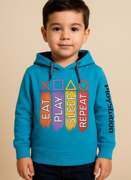 A young boy wearing a bright blue hoodie with "EAT PLAY SLEEP REPEAT" in colorful vertical bars and PlayStation symbols above, and "PlayStation" written vertically on the right sleeve.