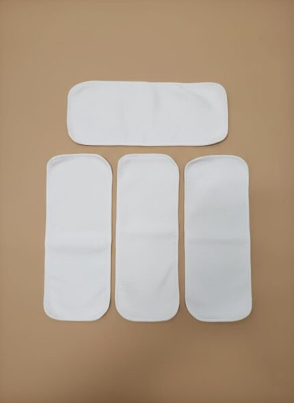 Five white reusable cloth diaper inserts, made of microfiber, arranged on a brown background, showcasing their soft texture and varying sizes for optimal absorbency in cloth diapers.