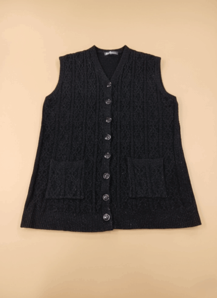Women's black cable knit sweater vest with buttons and pockets on a beige background