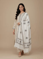 embroidered shawl in off-white with black and brown floral and geometric embroidery patterns and tassels.