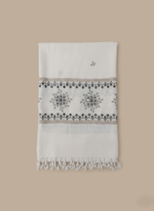 Hand-embroidered mirror work shawl in off-white with black and brown floral and geometric embroidery patterns and tassels.