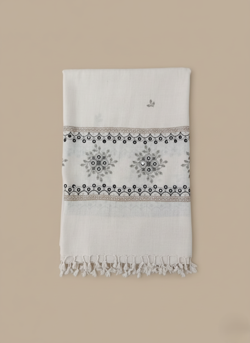 Hand-embroidered mirror work shawl in off-white with black and brown floral and geometric embroidery patterns and tassels.