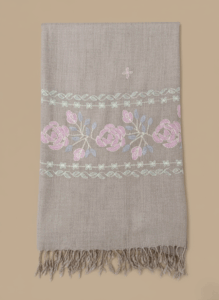 Hand-embroidered pashmina shawl with pink and blue floral embroidery on a beige background and fringed edges.