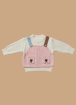 Flat lay of a pink knit overall top with embroidered pockets over a white ribbed baby sweater