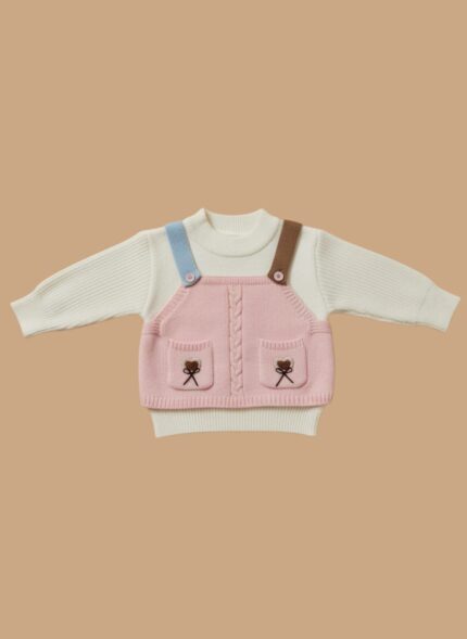 Flat lay of a pink knit overall top with embroidered pockets over a white ribbed baby sweater