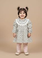 Smiling baby girl in black and white polka dot dress with lace collar, pink polka dot leggings, and white ballet flats.
