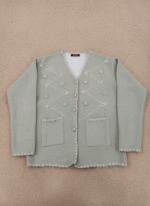 Women's sage green V-neck embellished button-front cardigan sweater with scallop trim and front pockets on a light brown background.