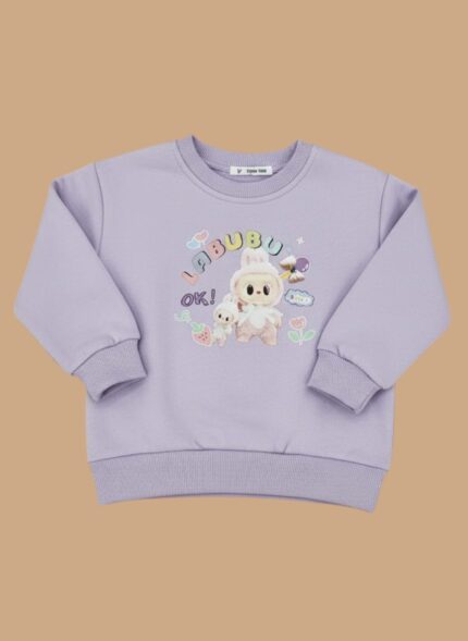 Toddler girl smiling in a purple bunny graphic sweater and blue jeans.