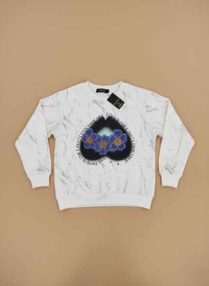 A white kids graphic sweater with a grey marble print, featuring a dark blue heart-shaped graphic with three blue and yellow flowers, lying flat on a beige background.