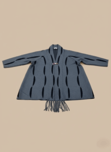 Women's grey kimono sweater with black wave pattern and fringe, front view, open-front knit, toggle closure.