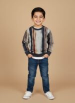 Boy wearing a striped multicolor kids sweater with grey, navy, and brown tones, styled with jeans and sneakers.