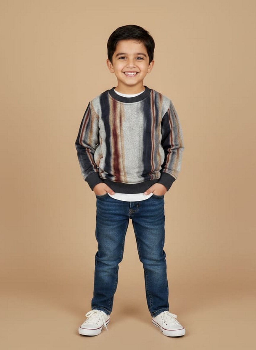 Striped Multicolor Kids Sweater Boy wearing a striped multicolor kids sweater with grey, navy, and brown tones, styled with jeans and sneakers.