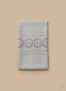 Soft grey embroidered shawl with detailed pink and blue floral and leaf embroidery, folded neatly against a light background.