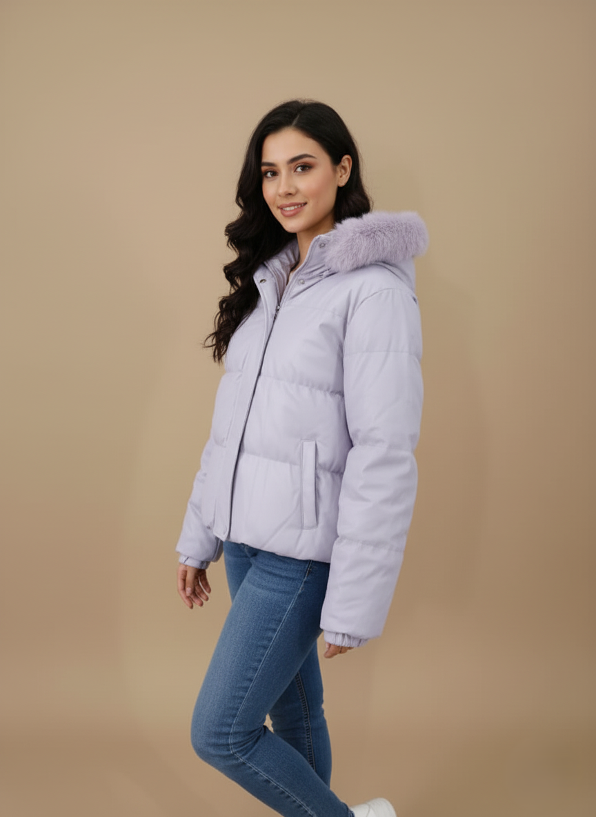 Women's Lilac Puffer Jacket Women's lilac puffer jacket with a faux fur-trimmed hood and cropped length, lying flat on a beige background.