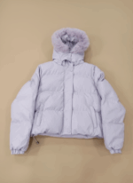 Women's lilac puffer jacket with a faux fur-trimmed hood and cropped length, lying flat on a beige background.