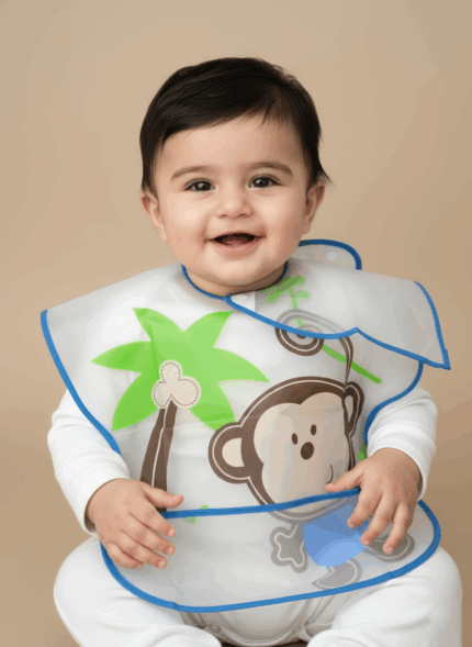A happy baby wearing a long-sleeve waterproof feeding bib with a monkey design, providing full coverage.
