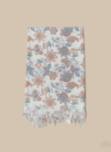 White floral print pashmina shawl with peach, teal, and blue flowers and butterflies, laid flat on a light background.