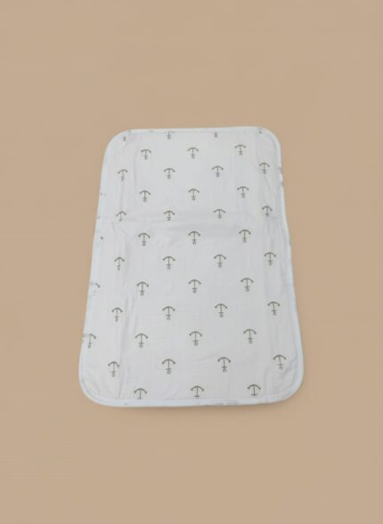A white baby swaddle blanket featuring a pattern of small grey anchors, laid flat on a light brown background.