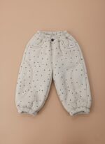 A pair of beige baby jogger pants with black polka dots, an elastic waist, and ribbed cuffs.
