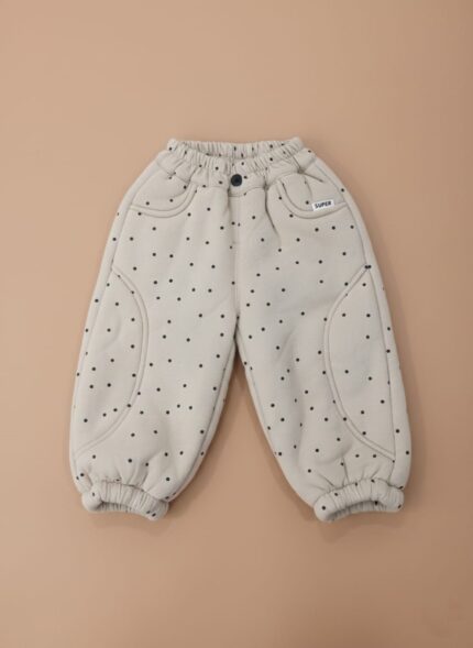 A pair of beige baby jogger pants with black polka dots, an elastic waist, and ribbed cuffs.