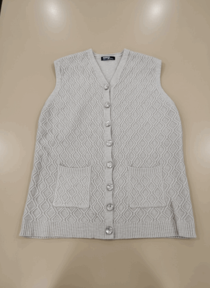 Light gray women's sweater vest with diamond knit pattern, clear decorative buttons down the front, and two front pockets, laid flat on a beige background.