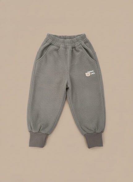A pair of grey ribbed baby pants with a bear embroidery on the pocket, an elastic waist, and cuffed ankles.
