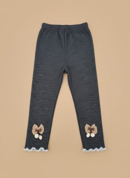 A pair of dark grey ribbed baby leggings with brown bows, white pom-poms, and ruffled white stitching on the ankles.
