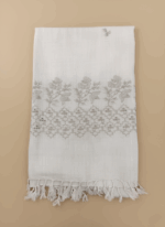 Hand-embroidered white cotton shawl with detailed floral and geometric embroidery, shown folded against a light background.