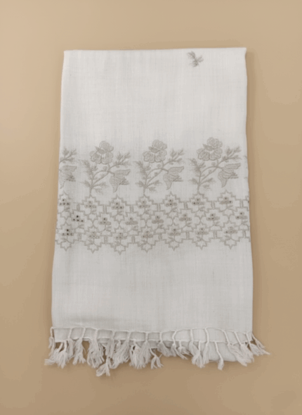 Hand-embroidered white cotton shawl with detailed floral and geometric embroidery, shown folded against a light background.
