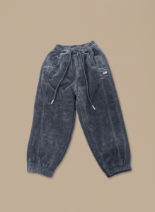 A pair of grey kids corduroy joggers made from ribbed corduroy fabric, with a drawstring waist and cuffed ankles.
