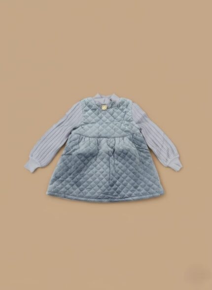 Blue quilted sweater dress for girls laid flat on beige background