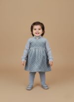 Toddler girl wearing blue quilted sweater dress and leggings, smiling in winter outfit