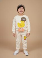 Boy wearing cream duck printed sweater and jogger pants smiling in winter outfit