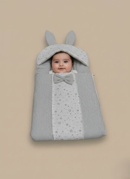 Grey baby sleeping bag with star print, bunny ears, and a bow on a neutral background.