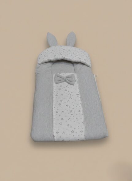 Grey baby sleeping bag with star print, bunny ears, and a bow on a neutral background.