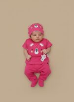 A cute newborn baby lying on a light background, wearing a bright hot pink, three-piece Koala-themed outfit with a koala face graphic on the shirt and hat.