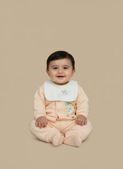 Baby wearing a light peach sweater with a white bib, featuring a cute animal appliqué on the sweater and embroidered clouds on the bib, paired with matching peach pants.