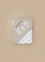 A newborn baby swaddled in a white blanket with green trim, featuring "YOU MAKE ME HAPPY" embroidered text, a teddy bear, an owl, and dinosaur patterns.