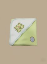 A newborn baby swaddled in a white blanket with green trim, featuring "YOU MAKE ME HAPPY" embroidered text, a teddy bear, an owl, and dinosaur patterns.