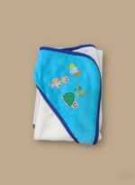 A newborn baby swaddled in a white blanket with green trim, featuring "YOU MAKE ME HAPPY" embroidered text, a teddy bear, an owl, and dinosaur patterns.