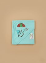 A newborn baby swaddled in a white blanket with green trim, featuring "YOU MAKE ME HAPPY" embroidered text, a teddy bear, an owl, and dinosaur patterns.