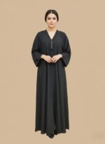 A woman in a full-length black abaya with subtle beading along the V-neck and down the front, accented with a black tassel.