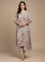 Full-length image of a woman wearing a beige Floral Embroidered Woolen Suit with red and pink floral patterns. The suit is unstitched, featuring a long shirt, trousers, and a dupatta, all made of warm wool fabric.