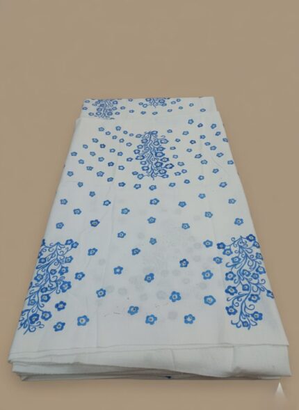 Folded white unstitched fabric with a blue hand-painted floral pattern and small blue flowers scattered across, ready for custom clothing creation.