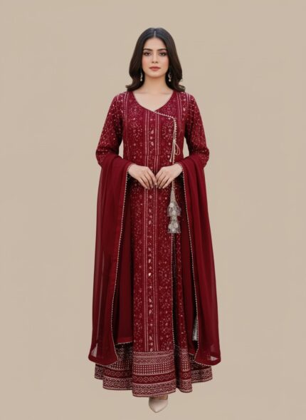 A woman wearing a vibrant maroon printed chiffon Anarkali style suit with a long-sleeved, flared kurta, matching maroon trousers, and a coordinating chiffon dupatta. The suit has intricate gold and silver prints and a decorative tassel.